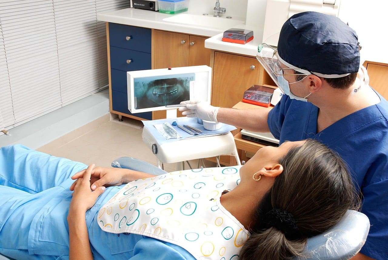A dentist shows a patient her X-ray on a screen