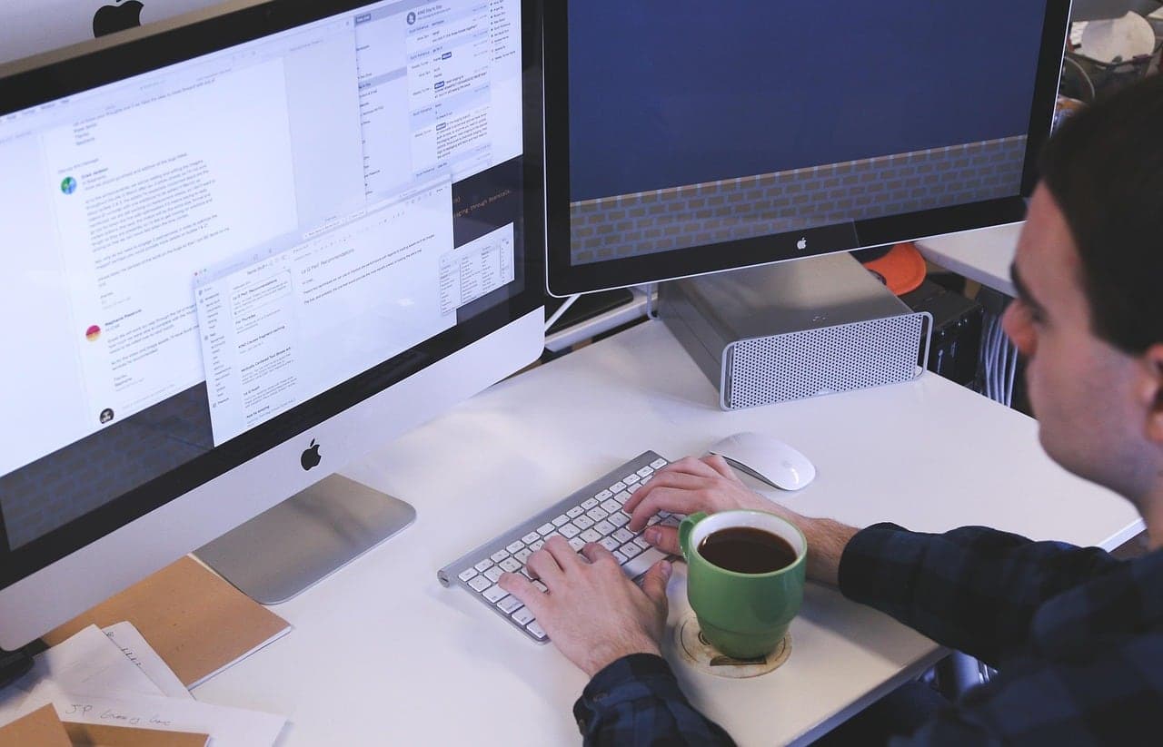 A man working through messages at his desktop with a coffee