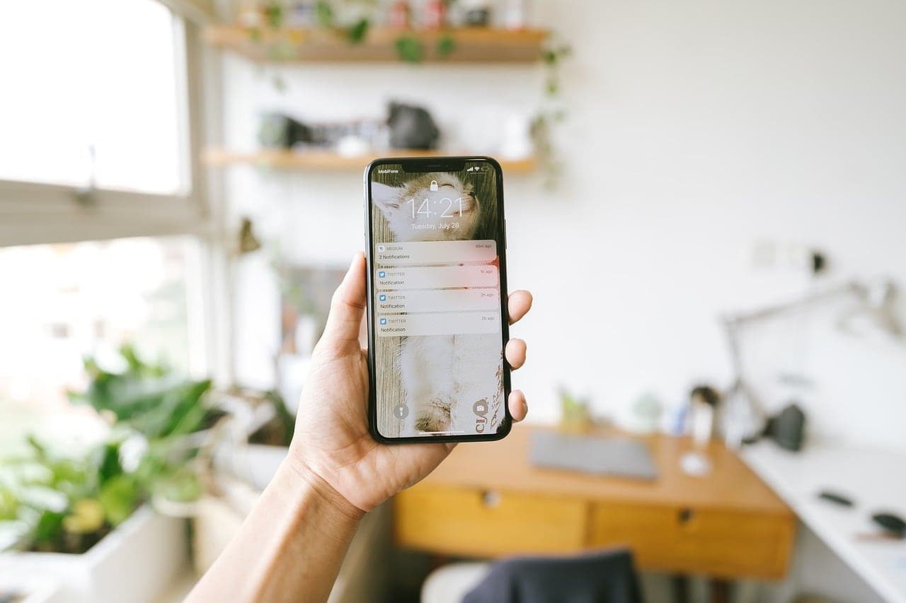A hand holding a phone with a message open in a bright room