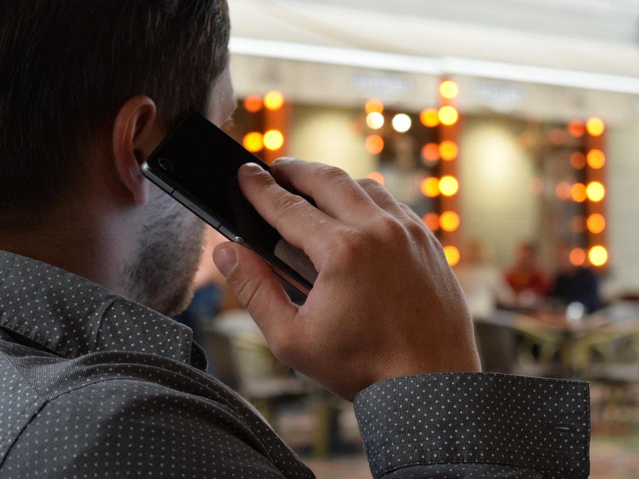 A man takes a call on his phone in a busy restaurant